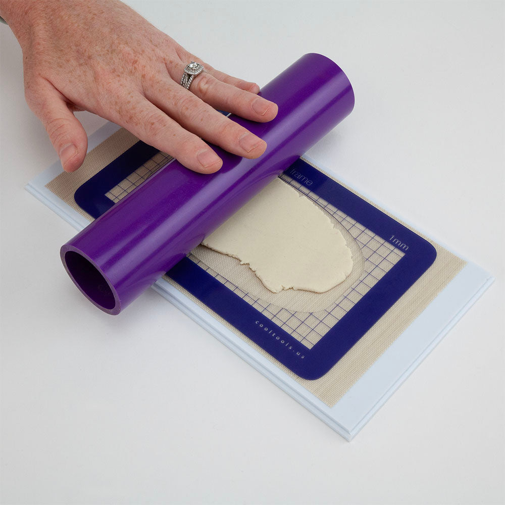 person rolling metal clay with purple roller on Cool Tools Clayboard Non-Stick Work Surface 4.5" x 9" with rolling frame