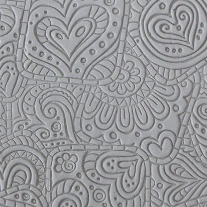 sample in clay of Mega Texture Tile - Doodling Hearts. Use to impress texture in soft clays. Mega Texture Tiles are perfect for projects both large and small. Mega Tiles measure 9-1/4" x 6" and are about 7 times larger than Texture Tiles. These textures are flexible, washable and can be used with any soft clay.