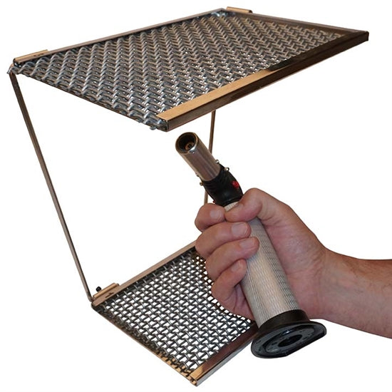 Whaley Wide-Open Soldering Platform with torch in persons hand. The Whaley Wide-Open Soldering Platform makes firing metal clay even easier. No more Tripod Legs! Ten-inch clearance with no obstructions. Comes with a set of fine mesh screens and a set of heavy-duty screens. One soldering surface is 6” X 6,” flip it over for another 6” X 9” surface. After use, the platform can be folded flat for storage or travel.